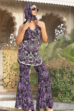 Woman wearing a purple paisley outfit with sunglasses in an outdoor setting.