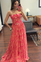 Woman in a red floral dress taking a mirror selfie in a room.