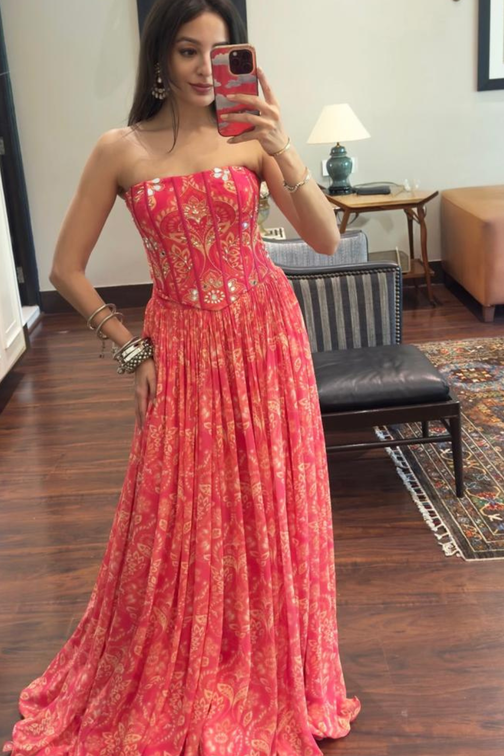 Woman in a red floral dress taking a mirror selfie in a room.