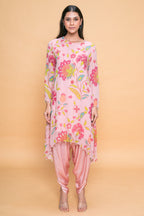 A woman modeling a floral rose tunic and dhoti set in pink shades, with embellishments such as sequins and pearls.