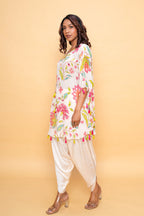 A woman modeling a white floral short kaftan with mirror embroidery and tassels, paired with light pink dhoti pants.